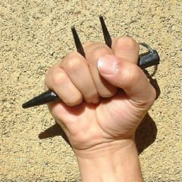hand holding three spiked kubaton keychain over tan background