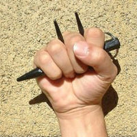 hand holding three spiked kubaton keychain over tan background