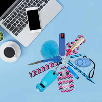 Self defense keychain with various tools on a blue surface next to a laptop and coffee cup.